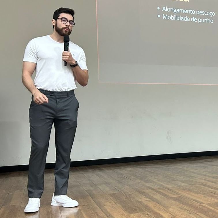 Barbosa dando uma palestra de microfone na mão, diante de um telão