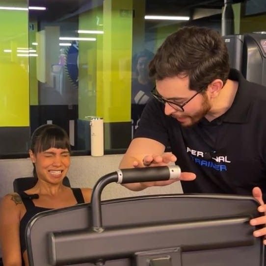 Barbosa orienta uma aluna durante um exercício em aparelho de academia