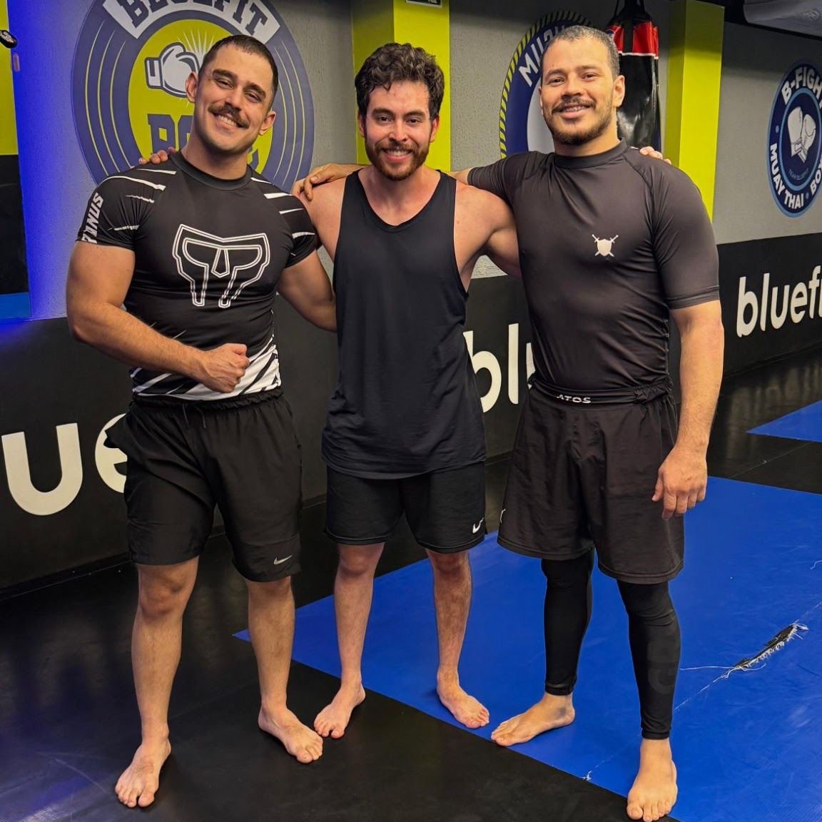Barbosa entre dois atletas no tatame de uma academia de lutas